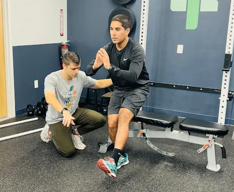 Trainer kneels beside a man balancing on a bench at Functionize Health & Physical Therapy in Dunwoody