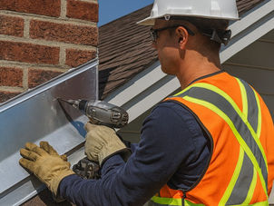 A professional roofer in Oak Park, Illinois, installs shiny metal roof flashing around a chimney under a clear sky, with the Oak Park Expert Roofing logo and company name in the bottom right corner.