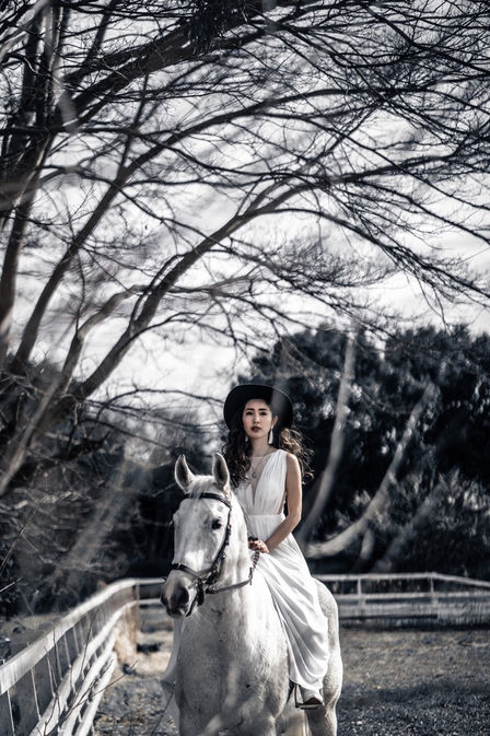 ウェディングドレスを着て乗馬をする女性