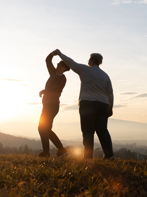 A couple dancing warmly in the field with sunset scene in the back