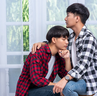 ชายหนุ่มสองคนนั่งประคองและเอาใจใส่กันในห้องริมหน้าต่างด้วยความอ่อนโยน สื่อถึงการโอบรับความจริงและการประคับประคองจิตใจเพื่อประสานรอยร้าว (Trauma-focused Recovery)