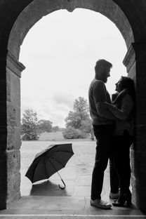 Silhouette of Jus and Gurdeep standing close under a stone archway with an umbrella nearby during their pre-wedding shoot in Nottingham, captured by RH Photography.