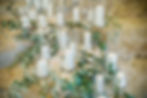 Church candles in glass vases surrounded with leafs on stone steps