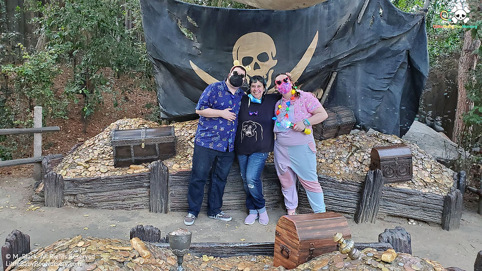Mommy Black and two littles posing by a pirate flag on a theme park adventure day.