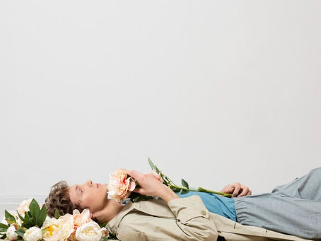 Stanchezza primaverile: uomo disteso con fiori, rappresentazione del mal di primavera e dell'astenia stagionale