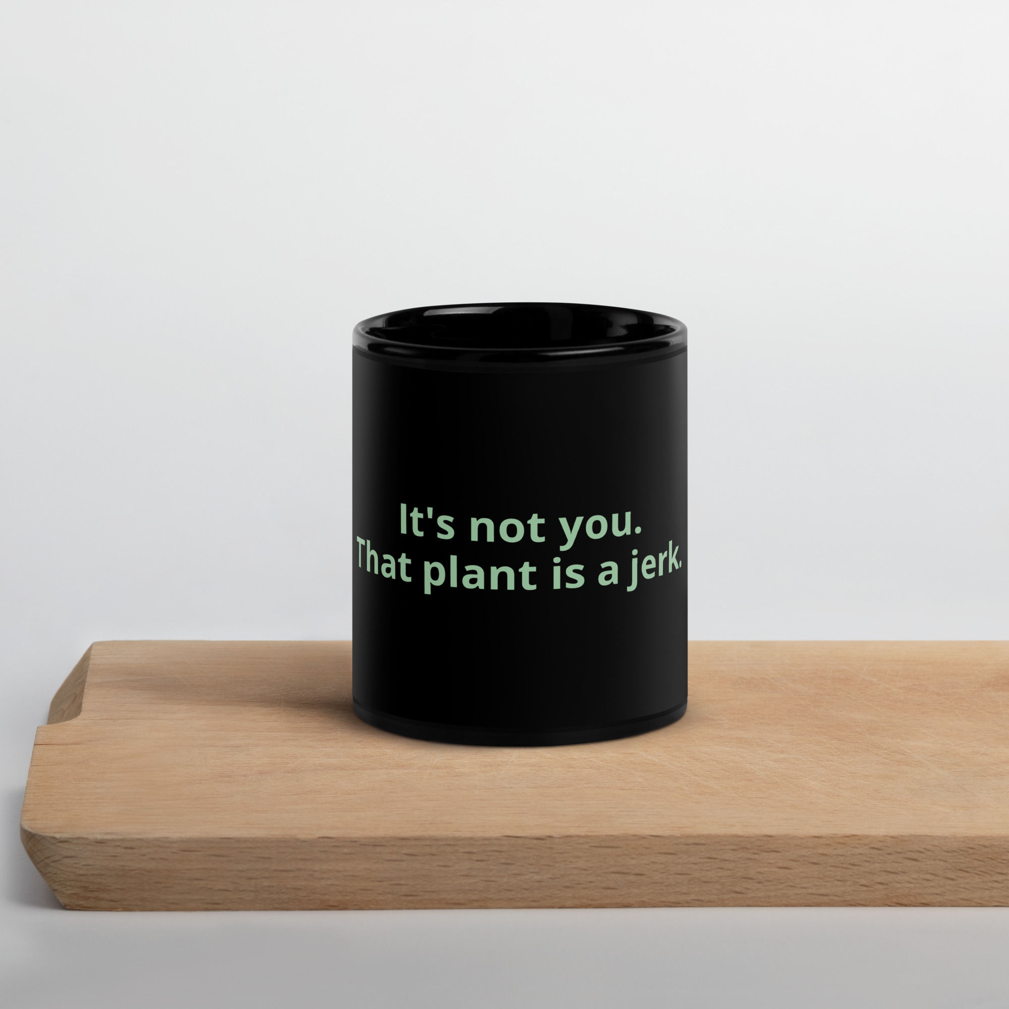 Black mug with 'Its not you, that plant is a jerk' slogan.