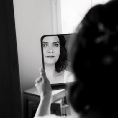 Mariée se regardant dans un miroir de main, noir et blanc.