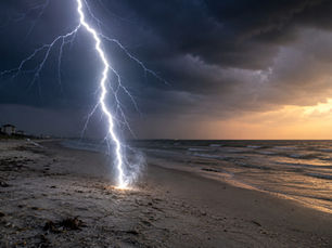 A lightning bolt strikes a sandy beach during a coastal thunderstorm, illustrating how lightning can turn silica-rich beach sand into natural glass called fulgurites.