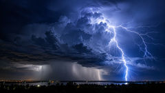 A brilliant forked lightning bolt illuminates a towering thunderstorm at night, showing how a single lightning strike can produce dramatically different thunder sounds, from a sharp boom to a long rolling rumble.