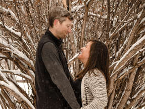 Couple dressing nicely gazing into each others eyes and embracing outdoors in the snow.