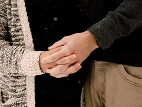 Arm of woman in sweater hold the hand of the arm of a man.