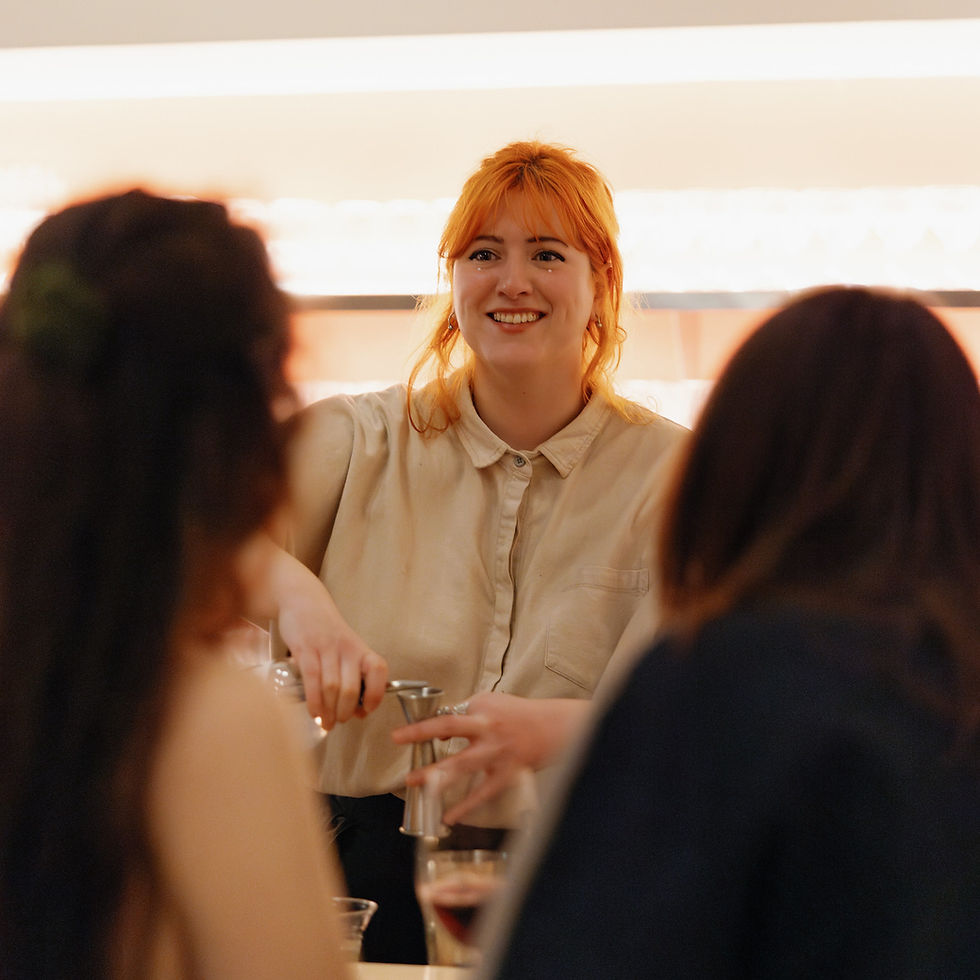 A Chowgirls bartender mixing a cocktail while talking with event guests.