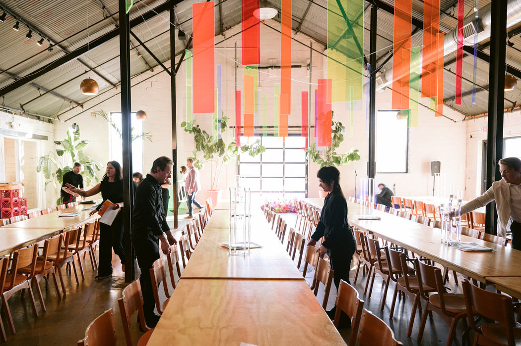 Chowgirls hospitality team members arranging chairs at the tables of an indoor wedding venue.
