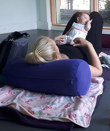 A Mother and baby layed on a yoga mat