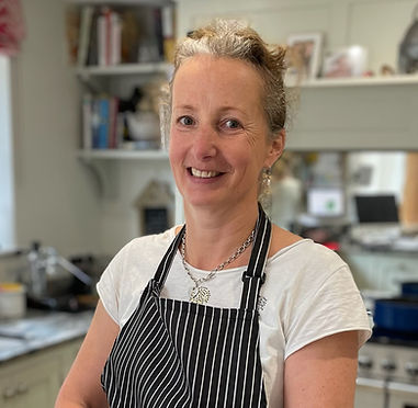 Clare smiles at the camera, wearing a stripy apron in her kitchen