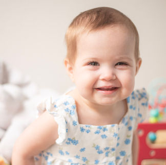 smiling natural light photo of toddler girl in blue and white romper