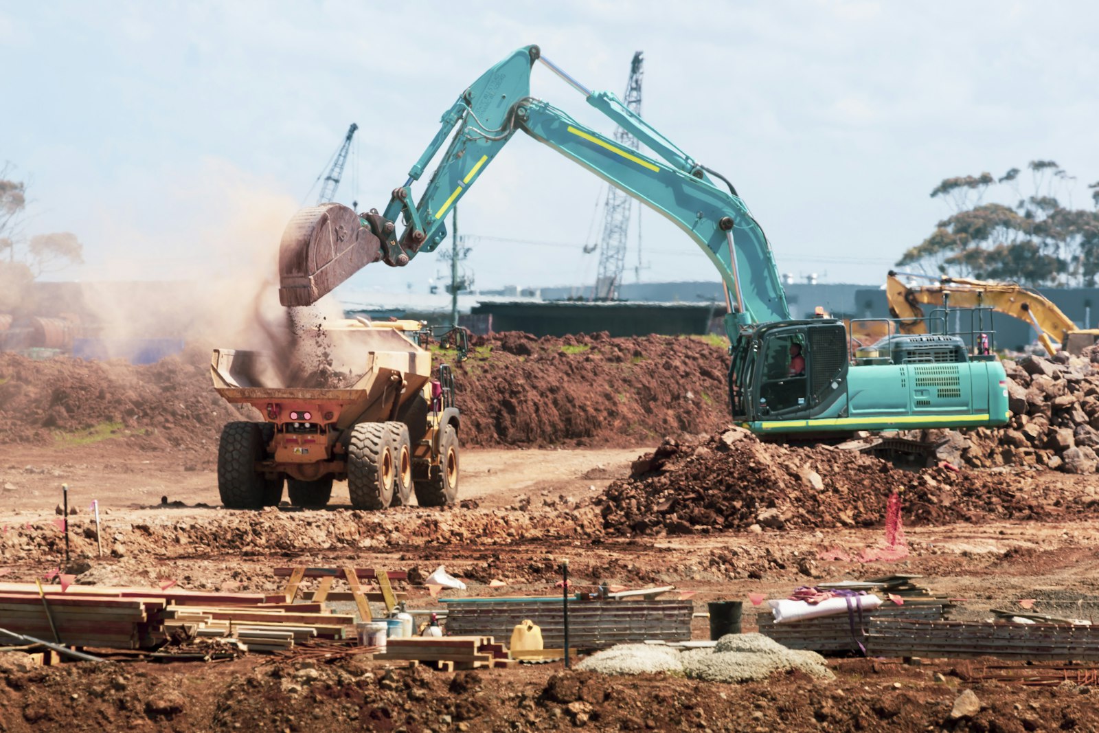 Excavator loading soil into a dump truck on a road construction site
