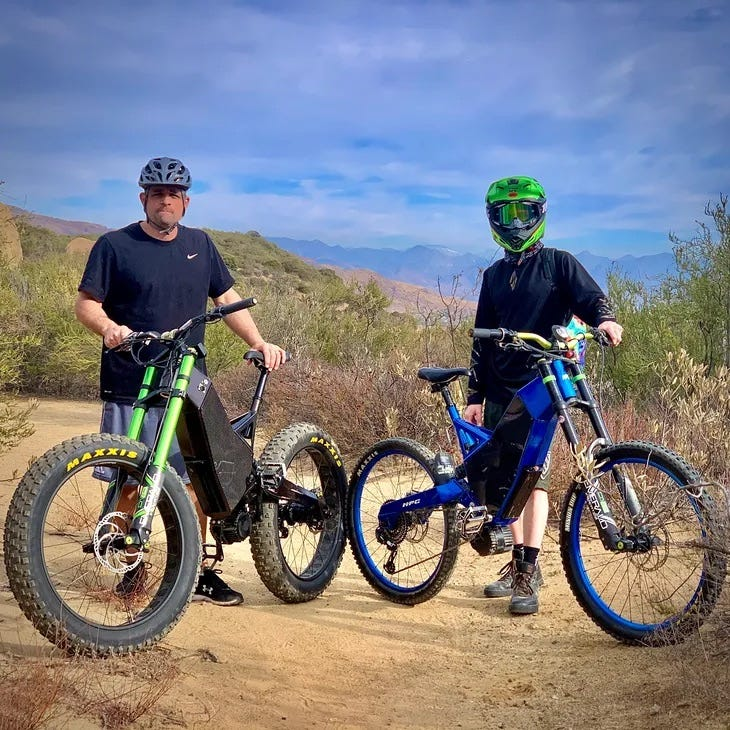 Two riders posing near their Revolution W electric bikes.