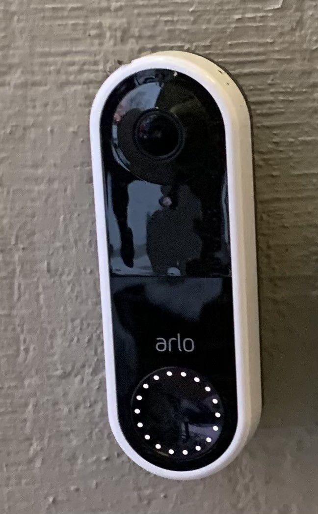 The Arlo wired essential doorbell is attached to the vertical surface adjacent to the door.