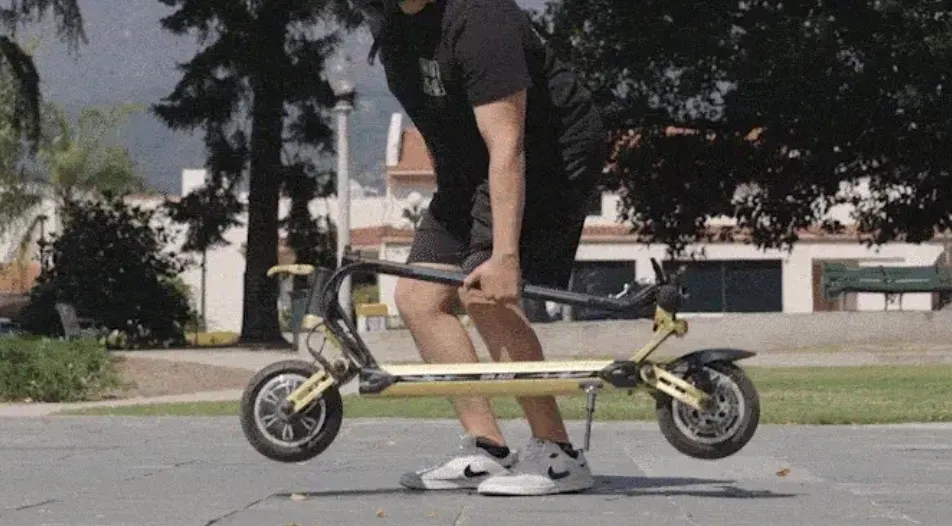 A Thunder electric scooter being picked up and carried after being folded.