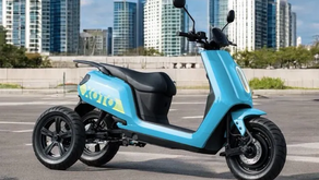 A view of the XOTO three-wheeled electric scooter with a city in the background 