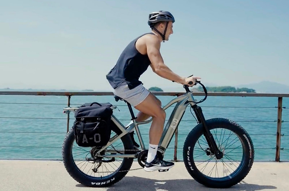A view of a rider on his Ronin electric bike as he is gliding down a beach road.