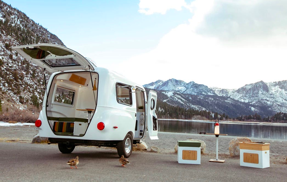 A parked Happier Camper with a few Adaptiv pieces being used outside of the actual camper.