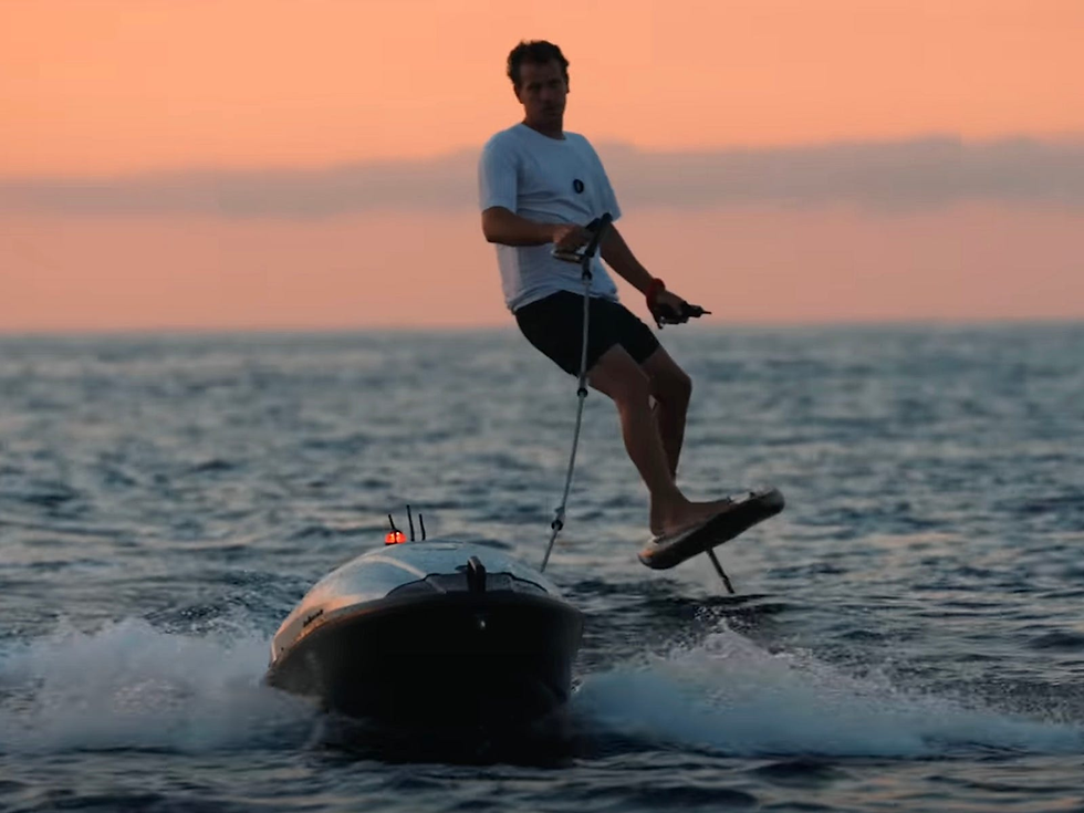 A foiler being towed by the eTow watercraft on open water.