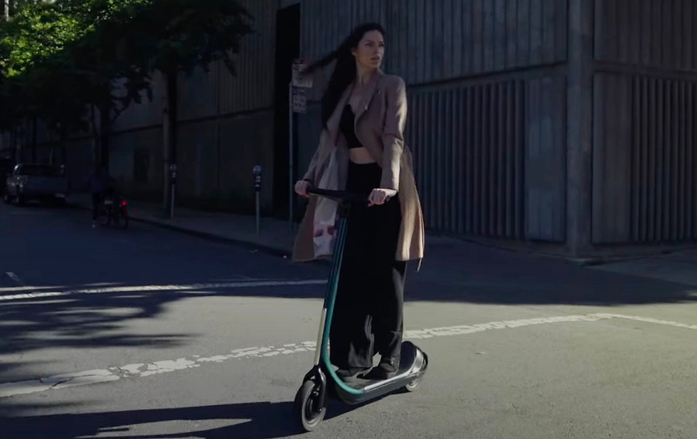 A female rider on her Scotsman scooter traversing a city street.