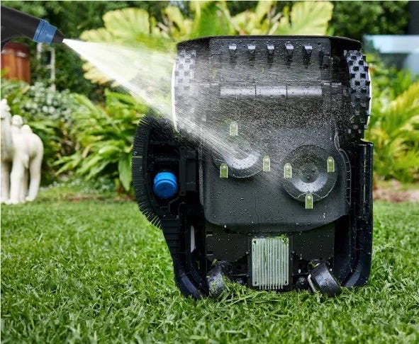 A hose being shown taking water to the underside of the Ecovacs GOAT G1 robotic mower in order to clean it. 