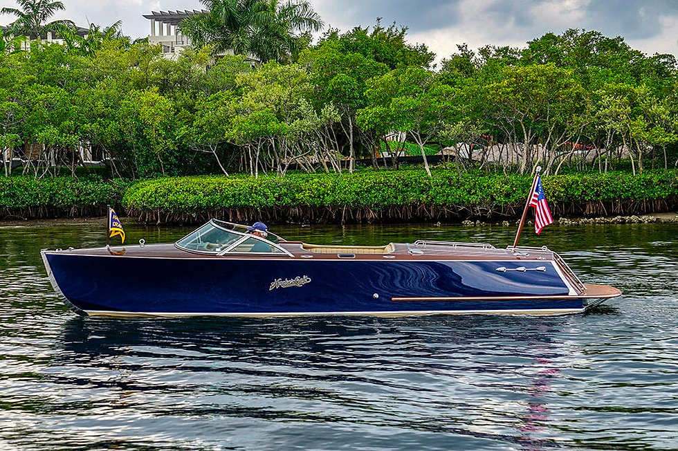 A view of a blue Sport luxury wood boat from Hacker-Craft smoothly exiting a no-wake zone.