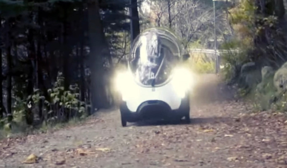 A Podcar Frikar traversing a concrete path with headlights on full beam.