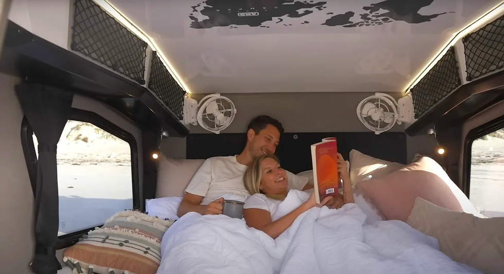 A couple enjoying relaxing time in the ARB Earth Camper's included queen bed.