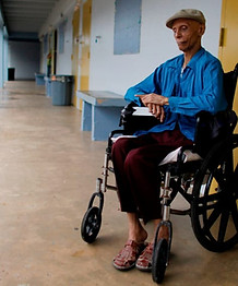 man in a wheelchair sitting outside his apartment door in a hallway