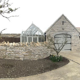 purbeck stone wall and green house of a property zoomed out view