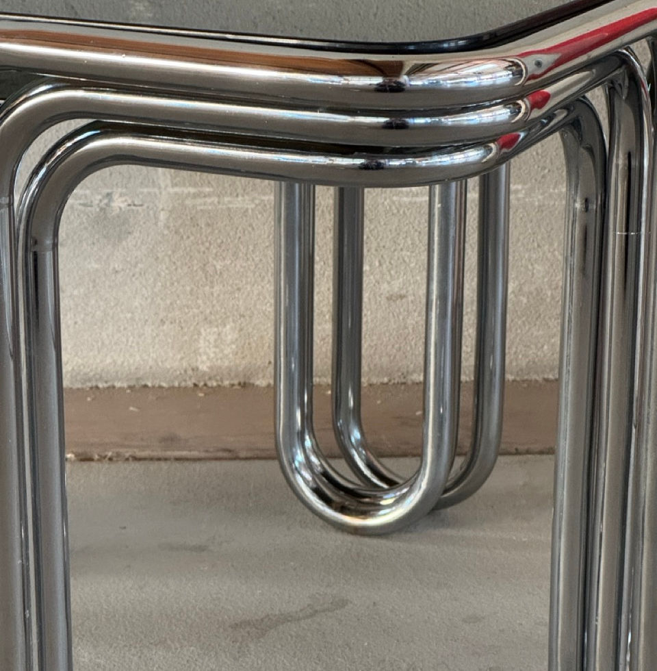 Close-up detail of the tubular chrome metal structure and U-shaped table legs