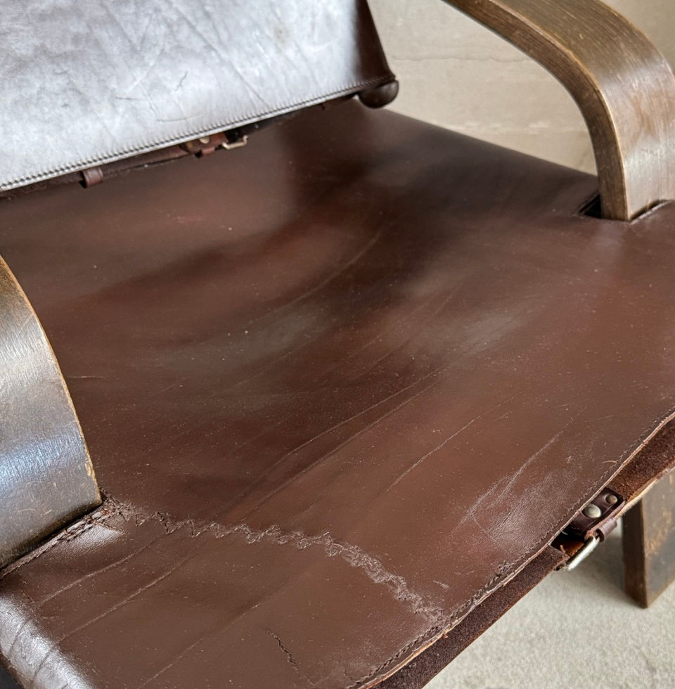 Close-up of the rich patina and texture on the saddle leather sling of the second chair