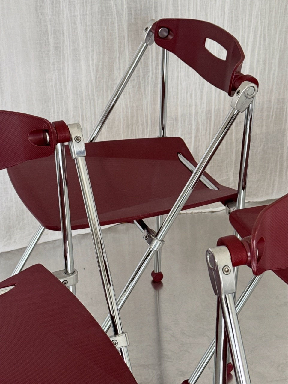 Detailed view of the wine-red polypropylene seats and chrome frame joints
