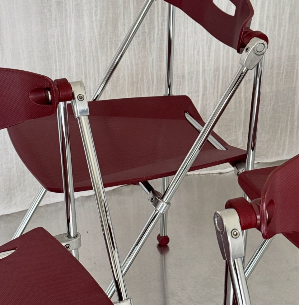 Detailed view of the wine-red polypropylene seats and chrome frame joints