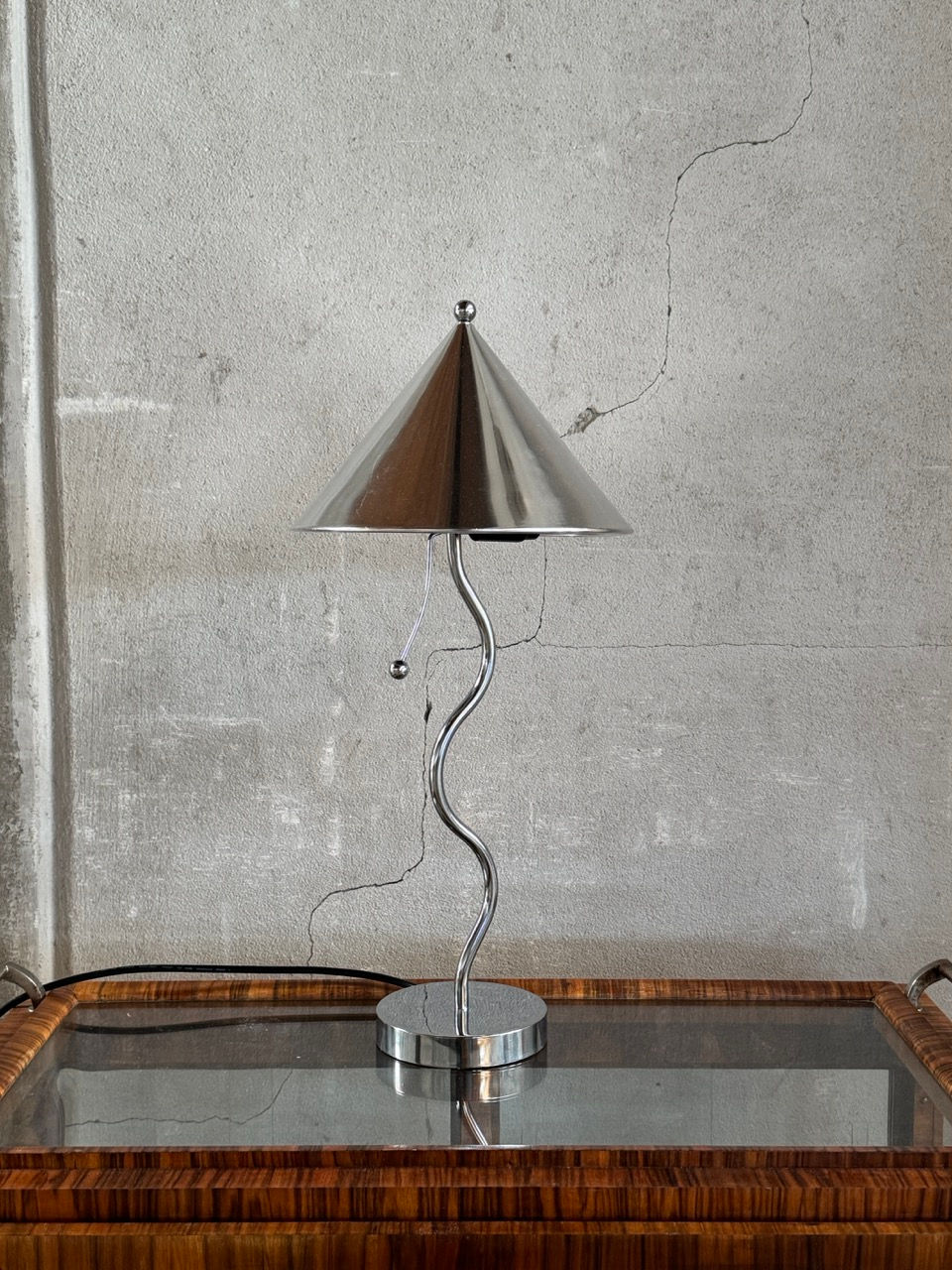 Postmodern 1980s chrome Pinocchio table lamp with wavy stem placed on a vintage trolley
