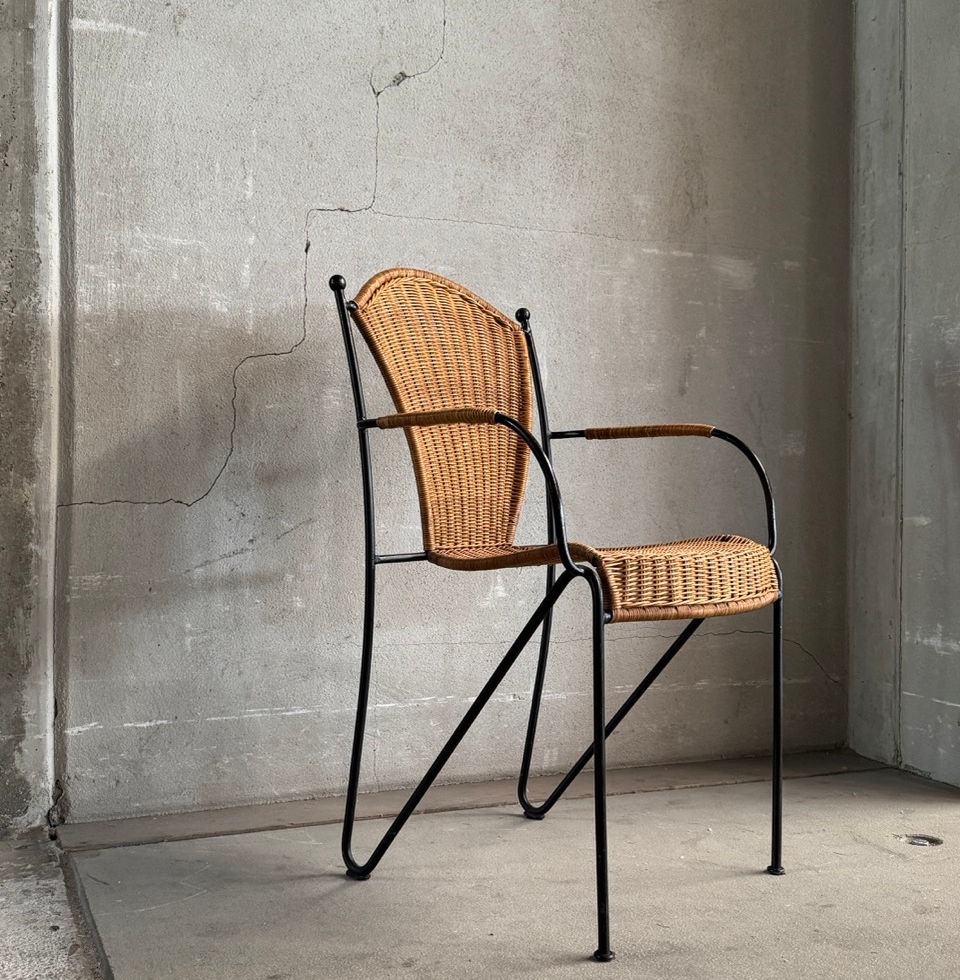 Side profile view of a Frederic Weinberg armchair with woven wicker seat and brass finials