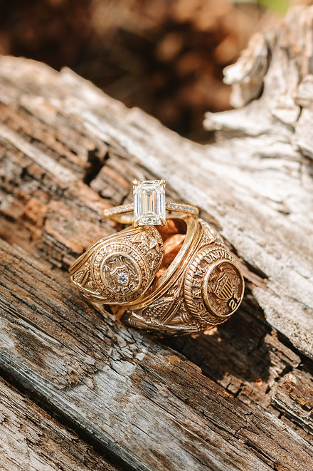 A close up image of an engagement ring with 2 Texas A&M University Aggie rings
