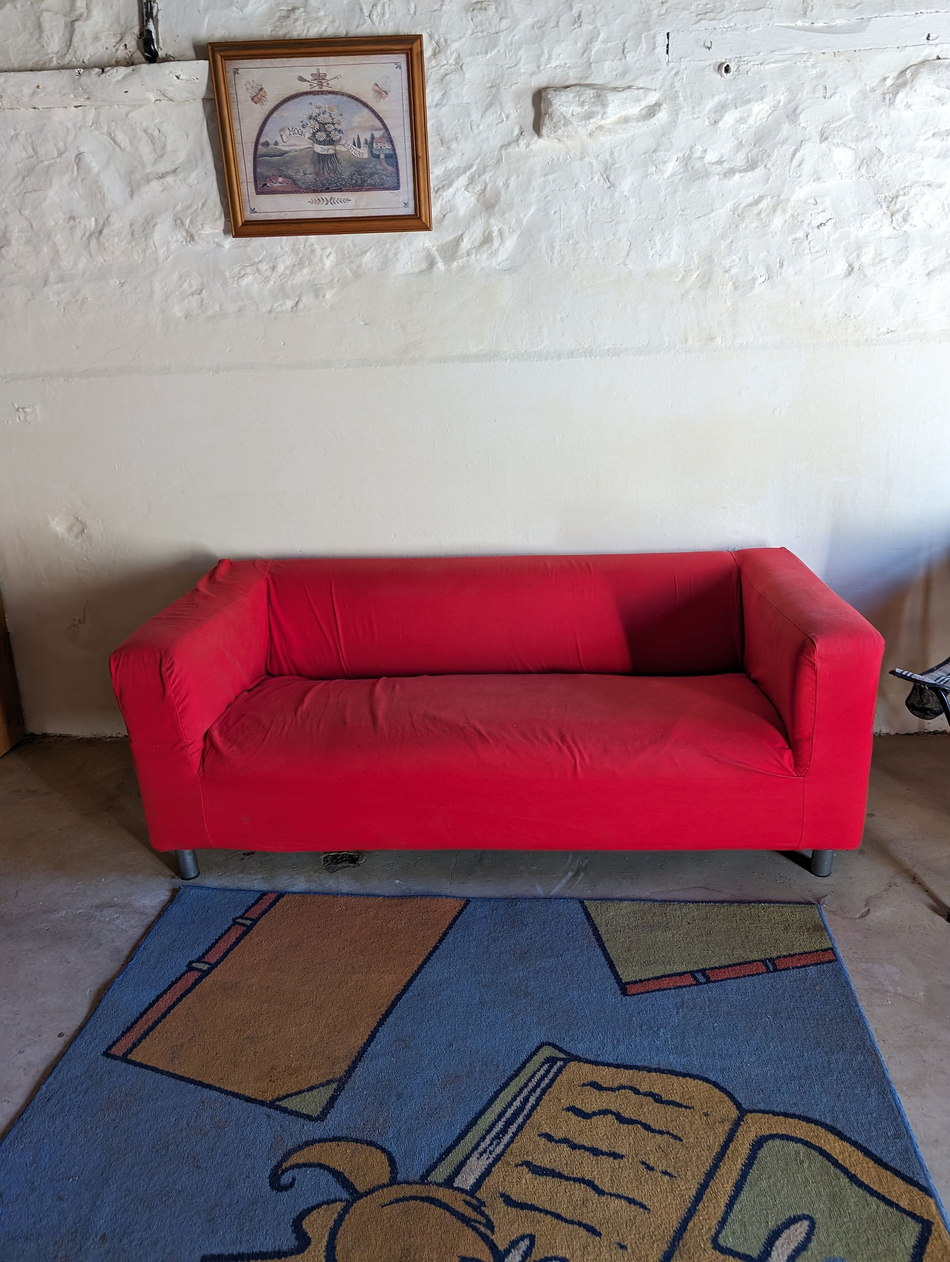 Large red sofa in front of a whitewashed wall in an outbuilding