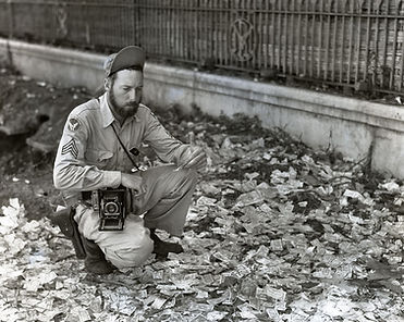 The_Photographer_Kneels_on_a_Street_Littered_with_Japanese_Invasion_Money_(BOND_0283).jpg