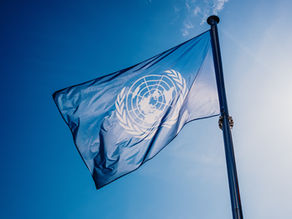 Le drapeau de l'ONU a agité contre le soleil et le ciel bleu.