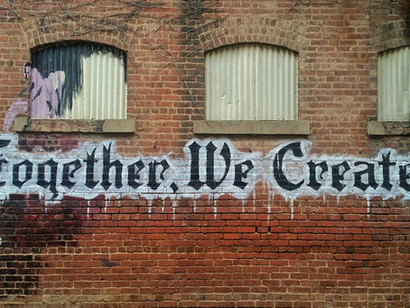 Graffiti message on a brick wall "Together, we create!"