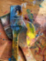 Emma Kinlough’s art studio with paint palettes, brushes, and a work in progress showing expressive color layers.