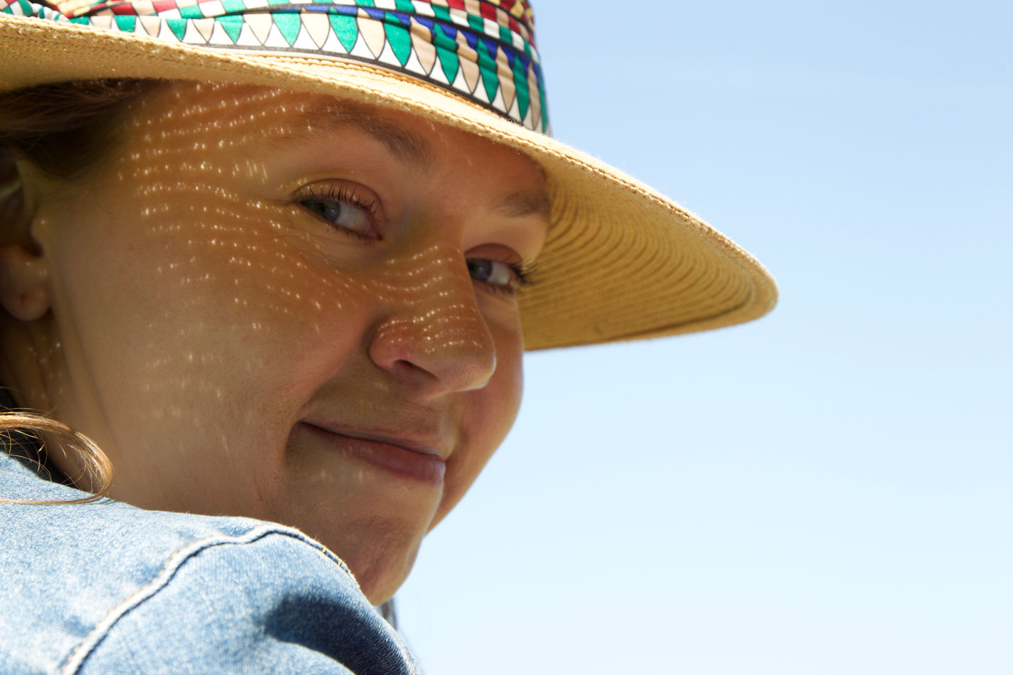 a portrait of a woman wearing a straw hat and the sun coming through making patterns on her face  taken by Ryan Mero Photographer 