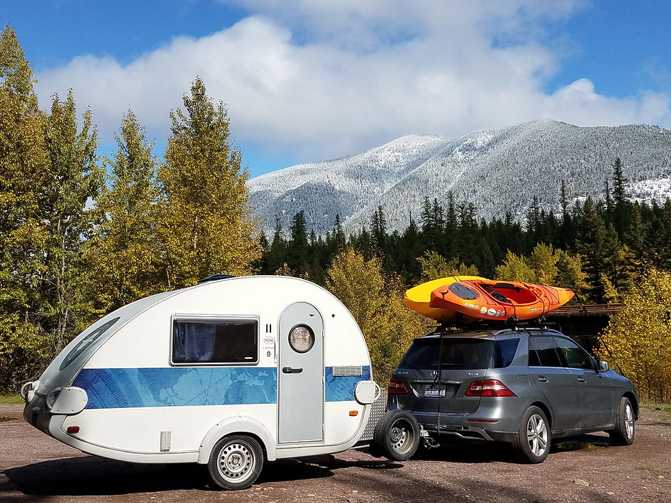 Teardrop trailer towed by an SUV with kayaks on top