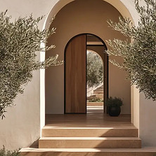 Mediterraner Hauseingang mit Olivenbäumen, hell verputzten Wänden und gewölbter Architektur.